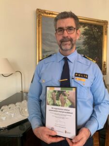 Bild av polischef med ett intyg i handen